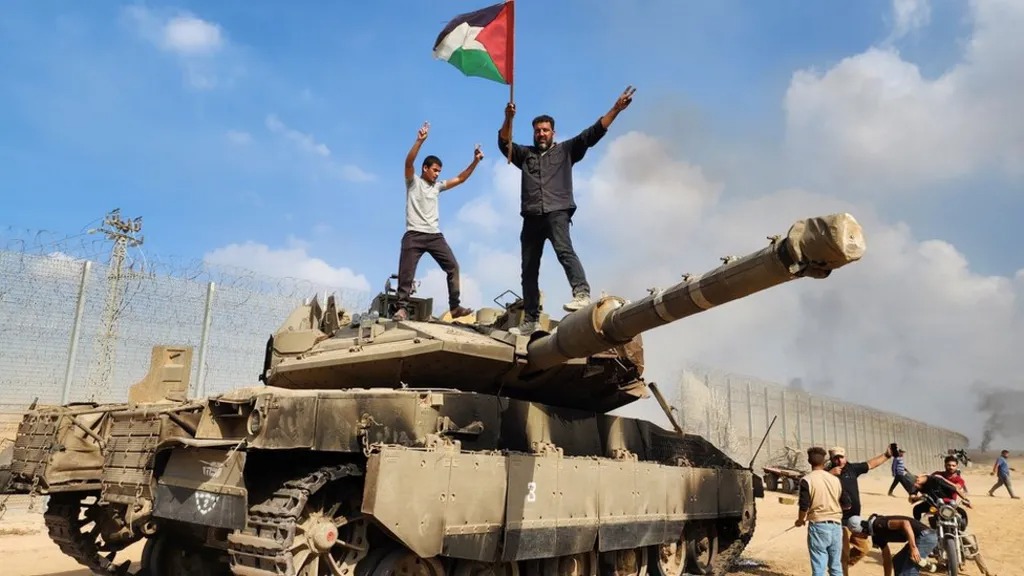 2023年10月7日，哈马斯战士在一辆被俘获的以色列坦克上挥舞巴勒斯坦国旗
